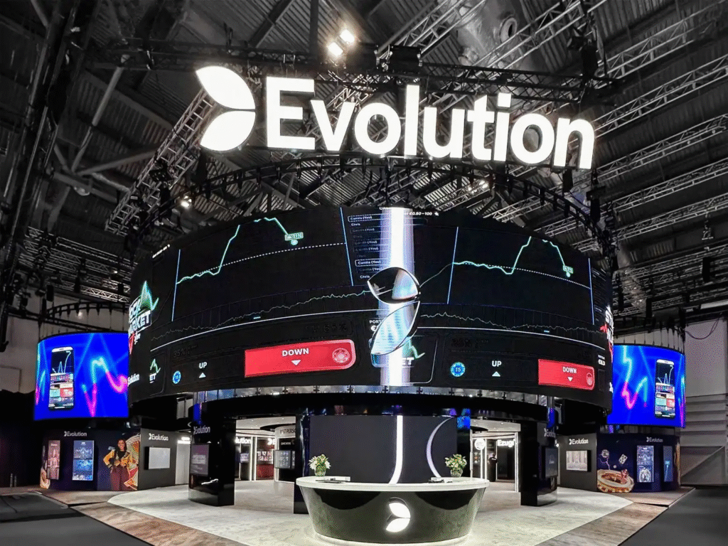 "A detailed image of Evolution Gaming's expo setup featuring a central large circular screen displaying real-time data with interactive elements like touchscreen counters, digital signage and surrounding walls, showcasing the blend of advanced technology and experiential marketing